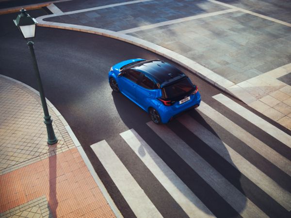 Vogelperspektive auf einen blauen Yaris, der über einen Zebrastreifen fährt.