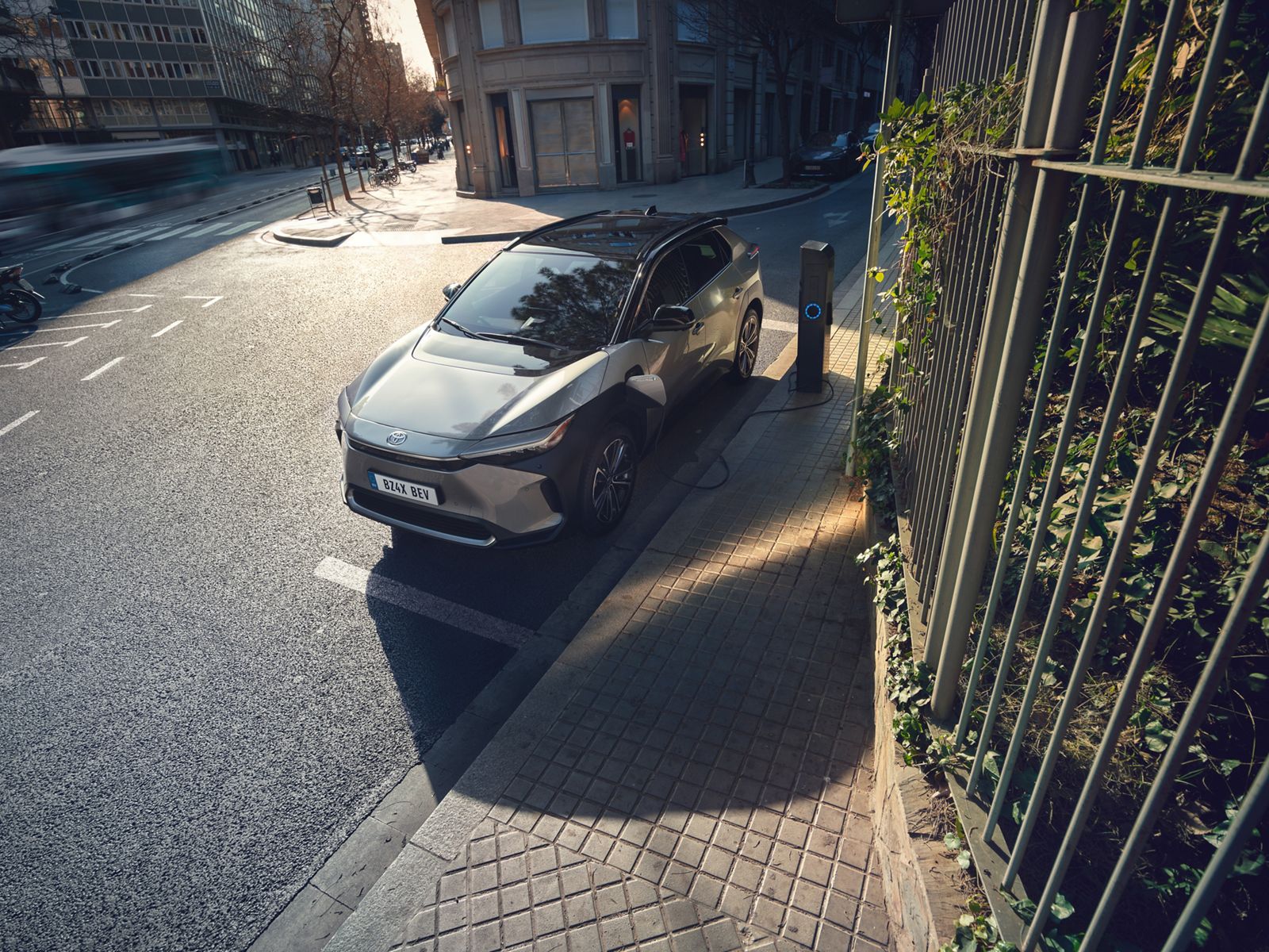 Ein silberner Toyota bZ4X steht geparkt am Straßenrand und lädt an einer Ladesäule.