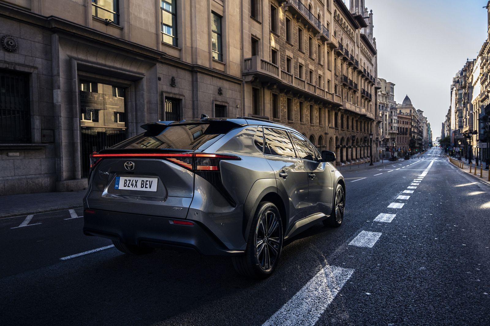 Blick auf das Heck eines Toyota bZ4X, der gerade durch eine Straße in einer Innenstadt fährt.
