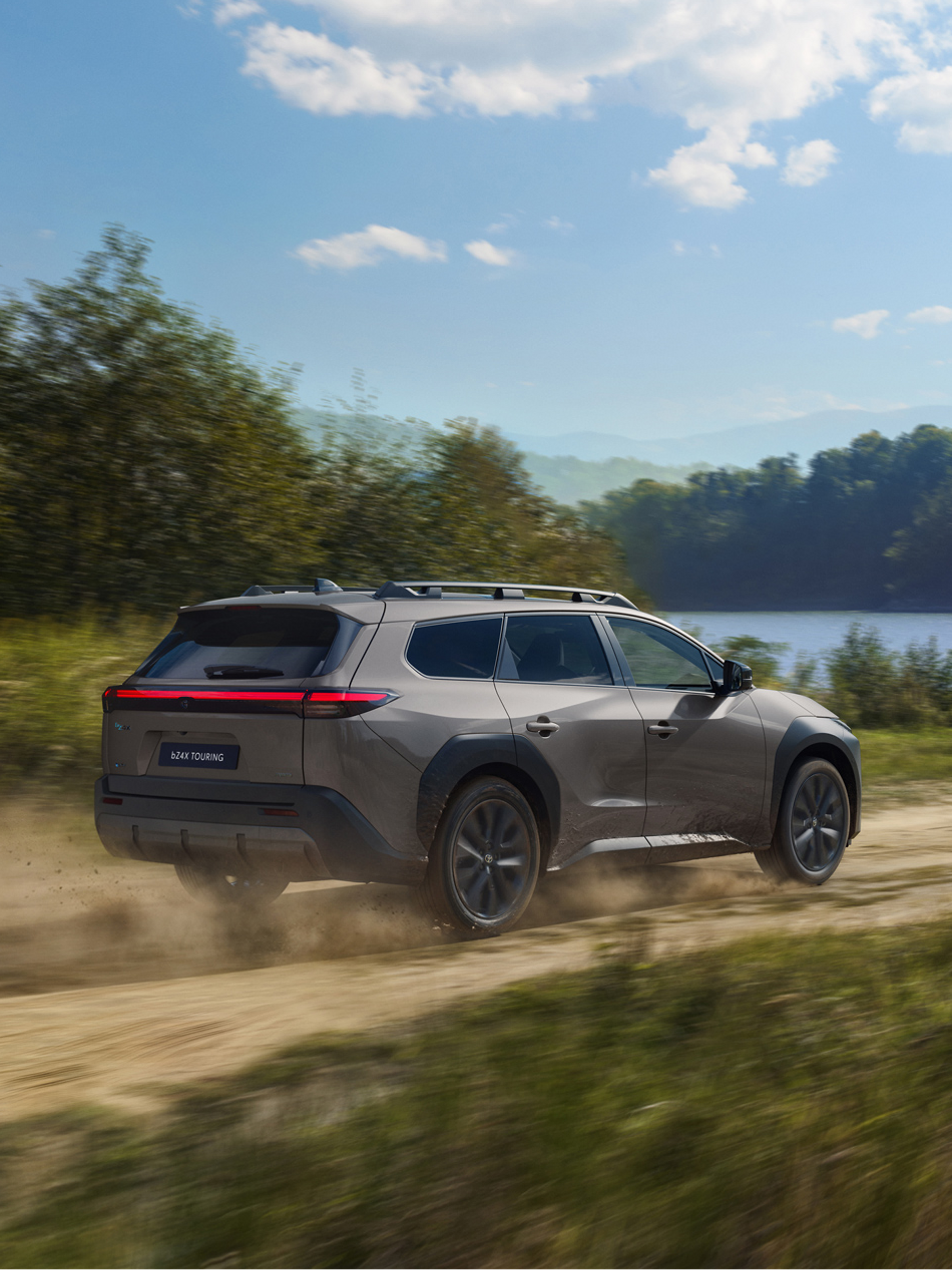 Grauer Toyota Elektro-SUV steht am Seitenrand und eine Person steckt den Ladestecker in die Seite. Dahinter ein modernes Bürogebäude.