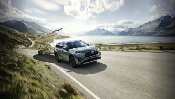 Toyota Highlander jedzie po drodze, holując łódź