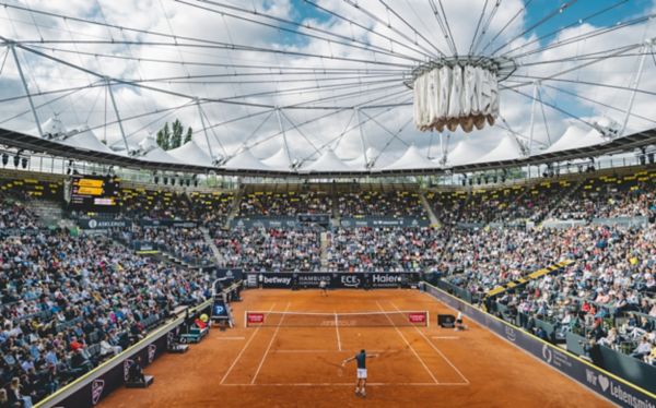 Zwei Personen spielen Tennis auf einem Tennisplatz vor Publikum