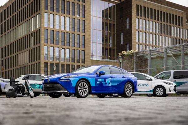 Tony Estanguet, Yoshihiro Nakata, Frank Marotte and Didier Gambart posing in fornt of the Paris 2024 car fleet with a blue Mirai in front and a white Kinto car and a white Corolla in the back