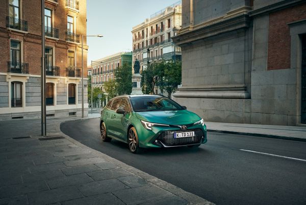 Ein grüner Toyota Corolla GR Sport auf einer menschenleeren Straße in der Stadt, im Hintergrund ein Boulevard mit Bäumen und einer Statue