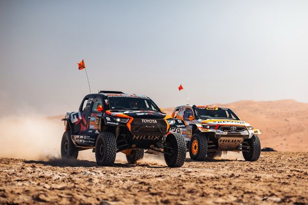 İki adet kumlu yolda giden Toyota Hilux
