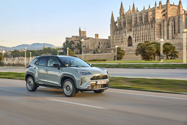 Ein hellgrauer Yaris Cross fährt auf einer leeren vierspurigen Straße, im Hintergrund Kathedrale und Altstadt von Palma de Mallorca