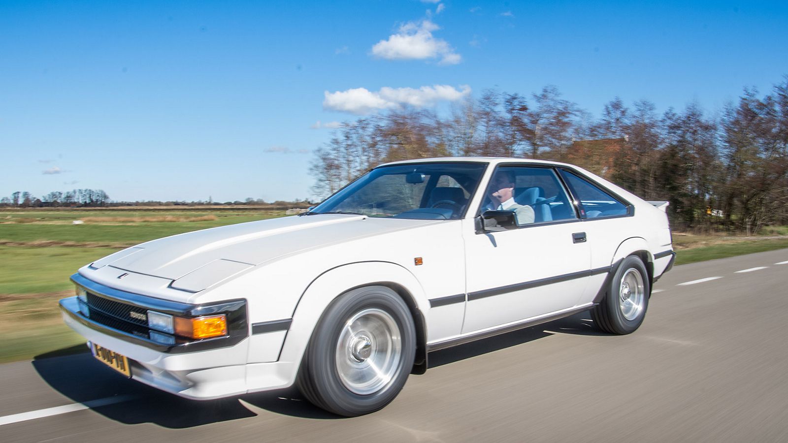 Toyota Celica Supra, exterieur, wit, linksvoor, rijdend langs boerderij