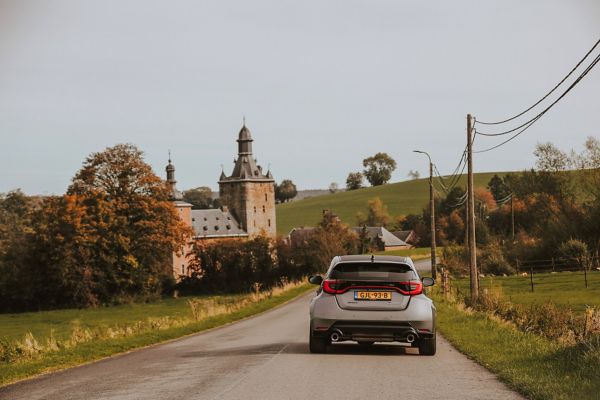 Toyota GR Yaris achterzijde rijdend op weg langs kasteel