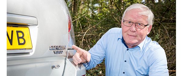 Toyota, Jan Schol wijst naar Toyota Corola Verso embleem, achterkant