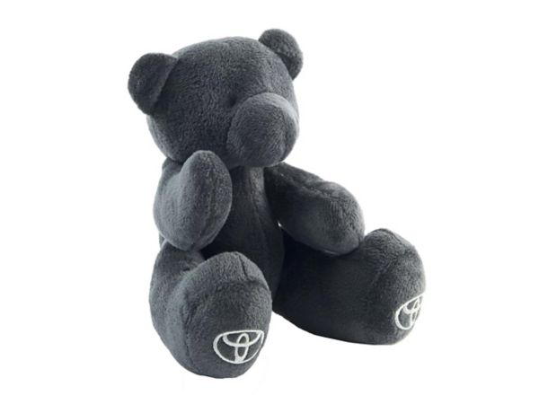 Ein sitzender grauer Teddybär mit gestickten Toyota-Logos auf seinen Pfoten