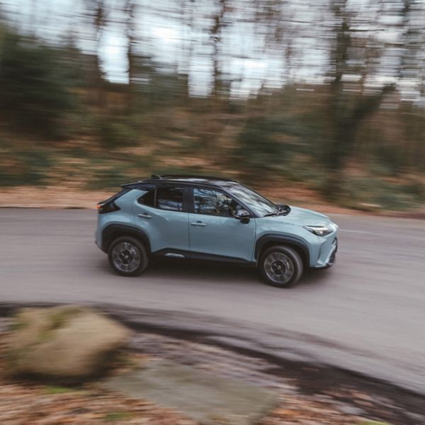 Toyota Yaris Cross, exterieur, zijaanzicht, dynamisch, bosrijke omgeving, slingerpad