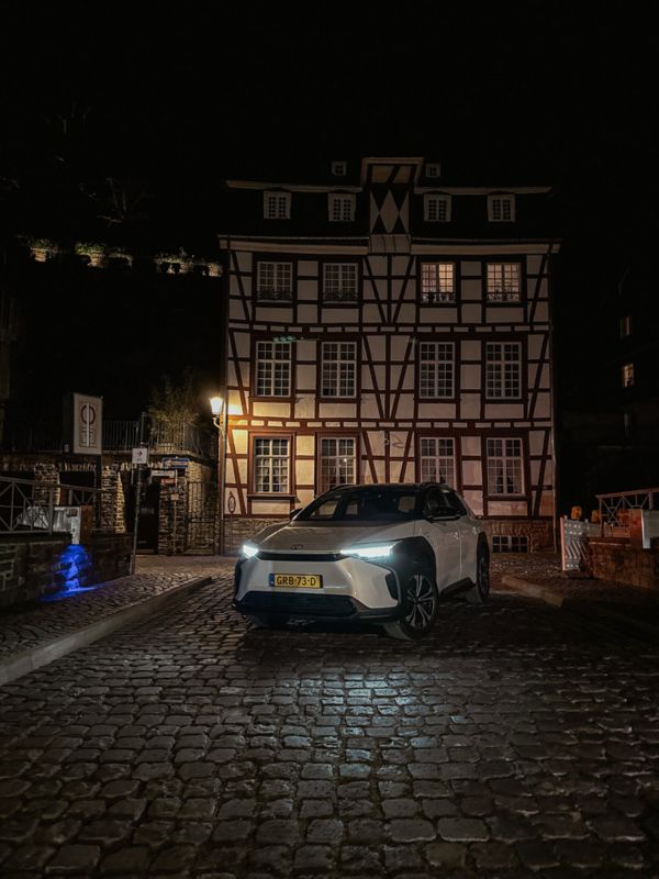 Toyota bZ4X Monschau schuin vooraanzicht nacht voor gebouw