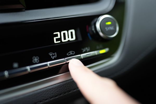 Toyota dashboard met verwarming op 20 graden en vinger drukt op recirculatiestand