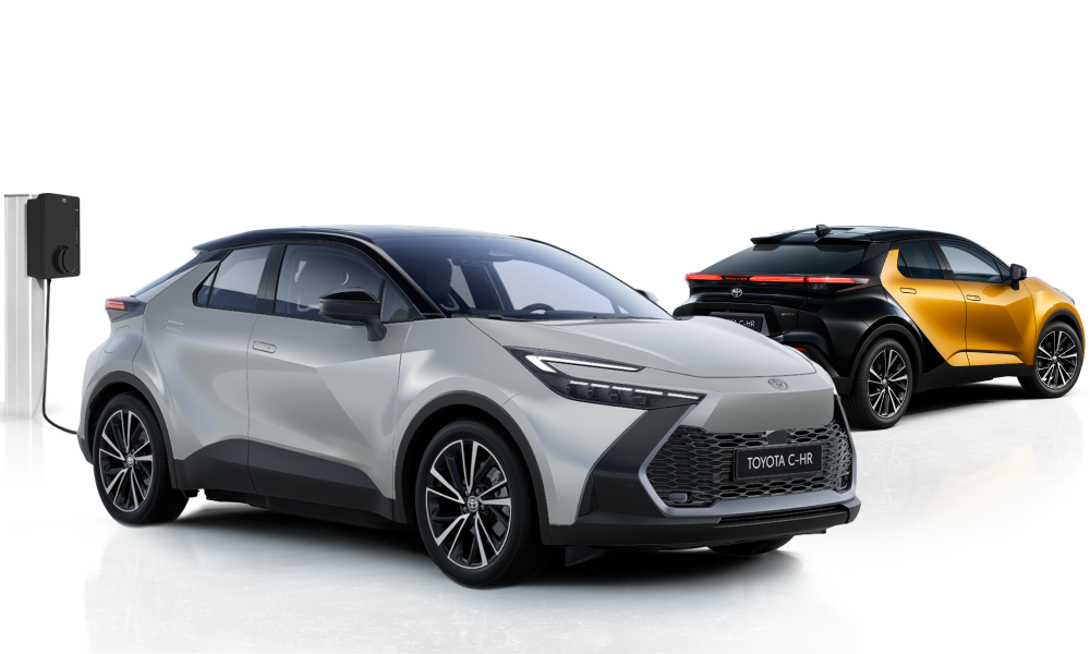 Ein silberner Toyota C-HR steht neben einer Ladesäule, dahinter steht ein schwarz-orangener Toyota C-HR