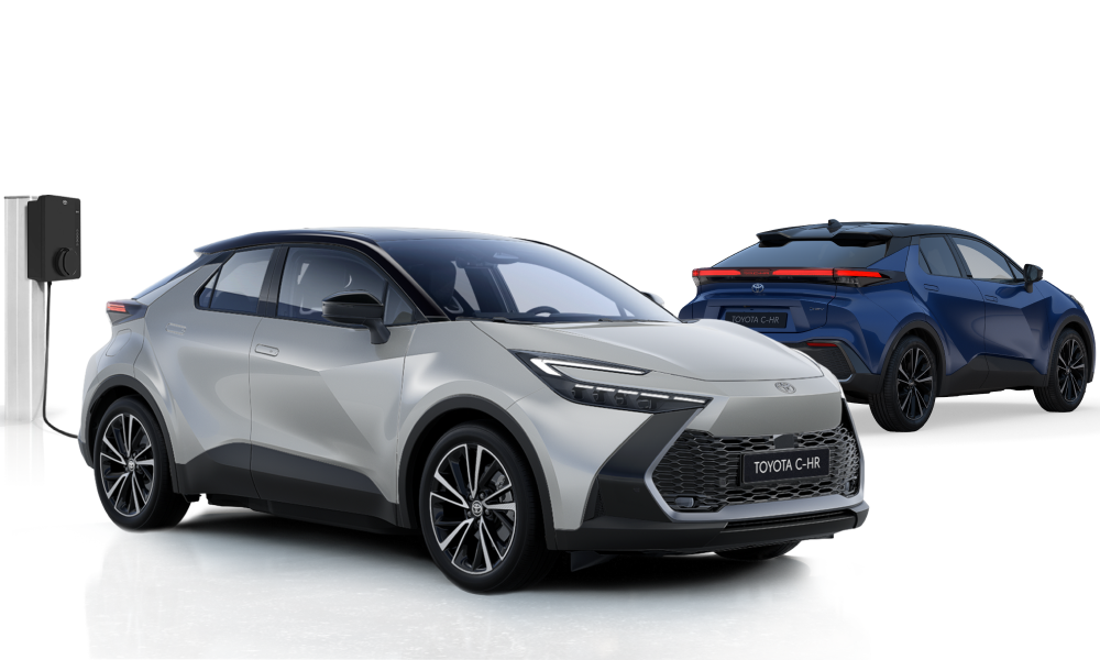 Ein silberner Toyota C-HR steht neben einer Ladesäule, dahinter steht ein schwarz-orangener Toyota C-HR
