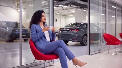 Toyota logosu önünde masada karşılıklı oturan bir kadın ve ona bir kitapçık uzatan bir adam