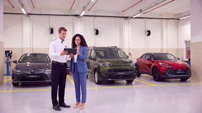 Elindeki Toyota Corolla kullanıcı el kitabını inceleyen takım elbiseli oturan bir adam