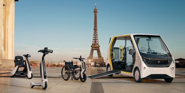 Toyota mobility products in front of the Eiffel Tower. The products shown are C+Walk s, C+Walk t, wheelchair e-puller Yosh-e and the Accessible People Mover APM