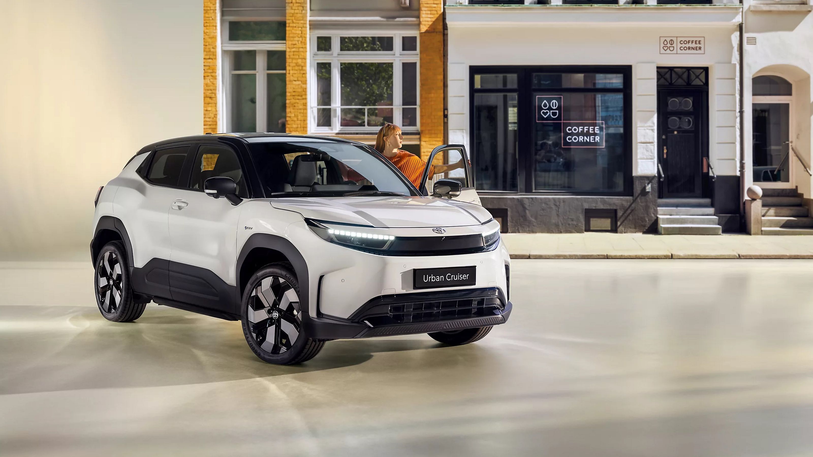 Toyota Urban Cruiser vor modernem Café – kompaktes SUV mit futuristischem Design in urbanem Umfeld, ideal für die Stadt, moderne Mobilität mit Lifestyle-Faktor.