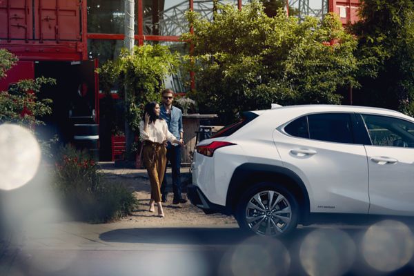 Two people walking behind a Lexus UX Hybrid.