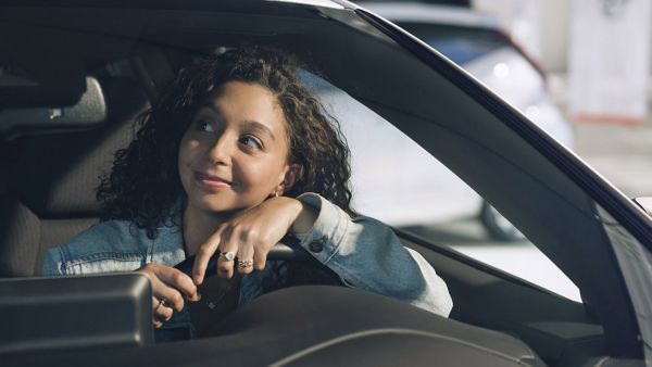 Vrouw achter stuur kijkt glimlachend uit raam Toyota