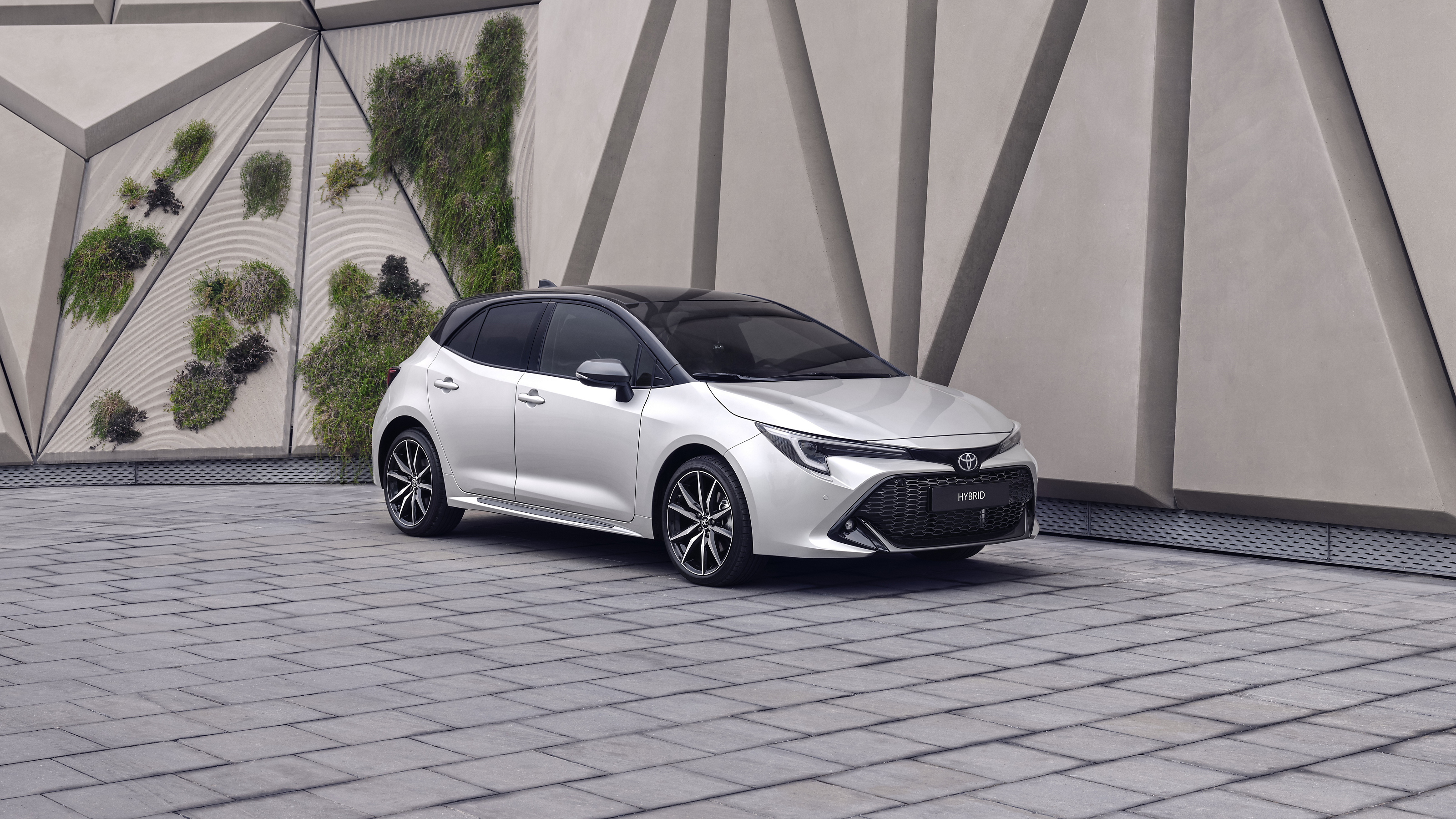 A Toyota Corolla Hatchback drives down an urban street