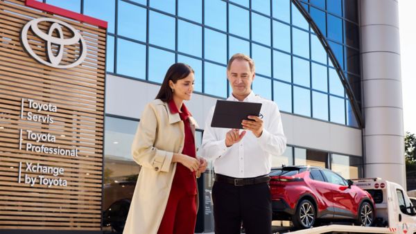 Bir müşteri Toyota çalışanıyla birlikte bayi önünde ekrana bakıyor