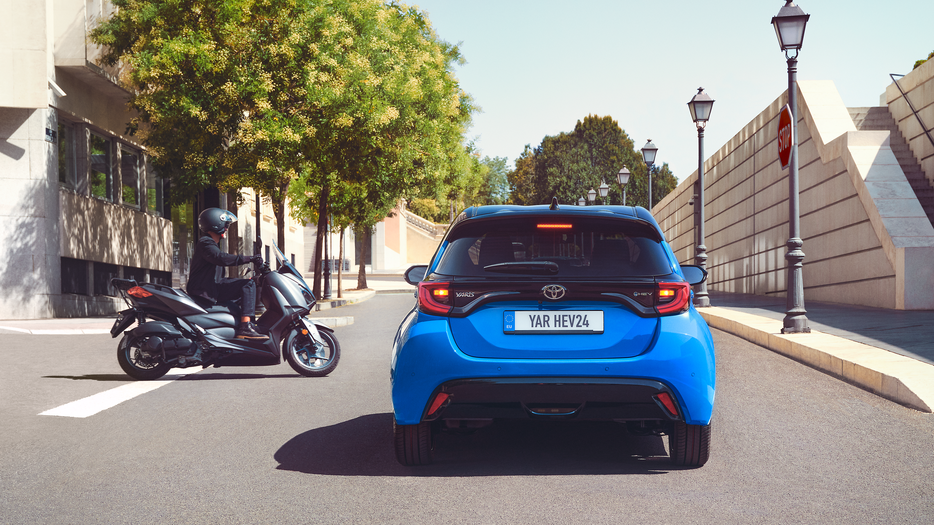 Full rear shot of the Yaris with scooter cutting the road