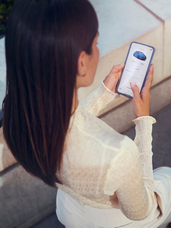 Un téléphone est posé près du levier de vitesse d’une Toyota. Son écran affiche la fonction d’assurance basée sur l’utilisation de l’appli MyT de Toyota.