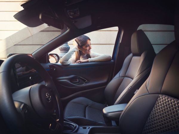 A Yaris customer leaning on the door of the car, appreciating the roomy interior