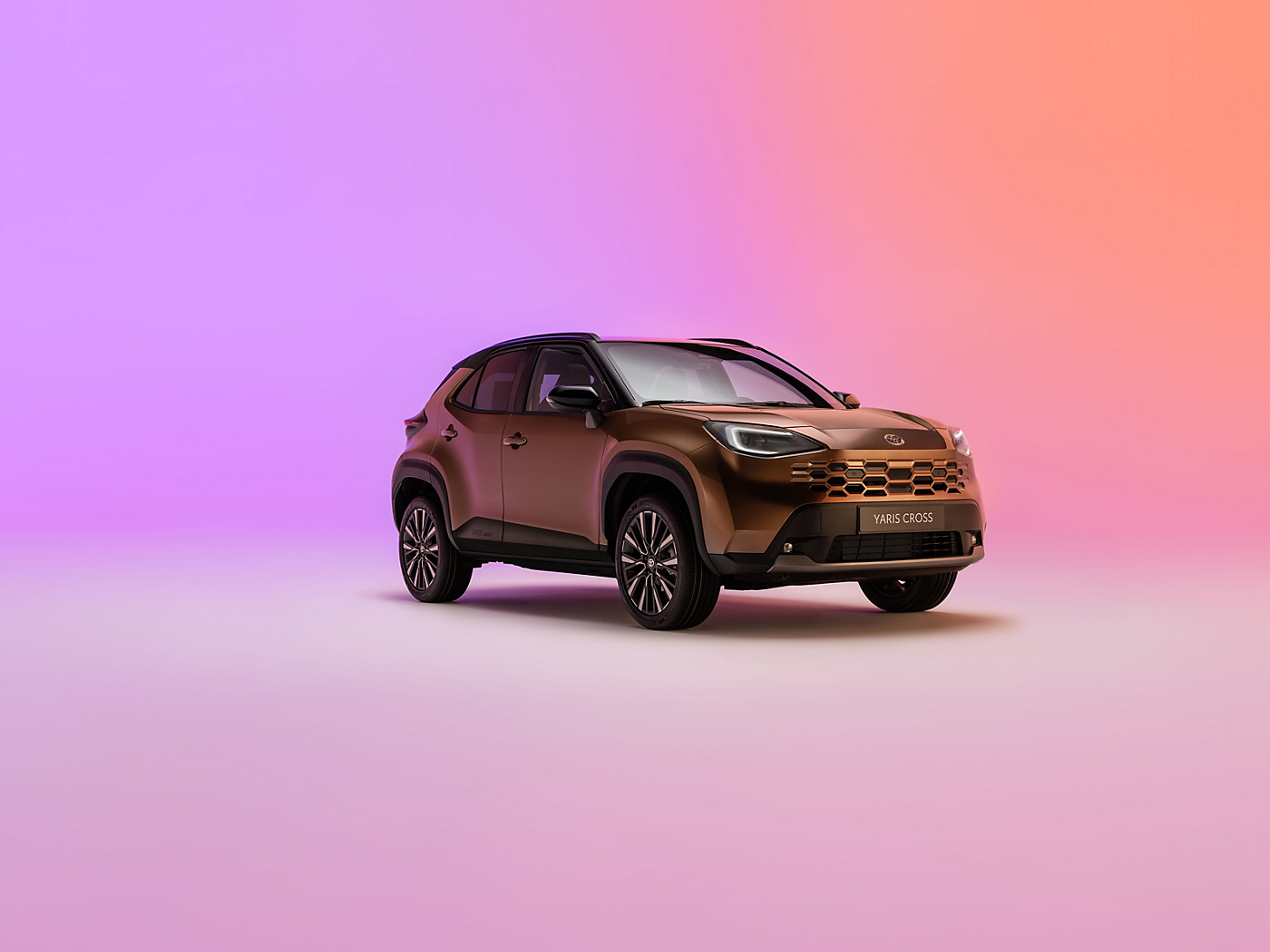 New Yaris Cross in a studio setting against a soft pink gradient background.