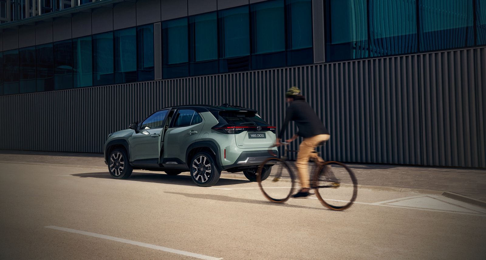 Fietser rijdt vlak langs een Yaris Cross waarvan de deur net open lijkt te gaan