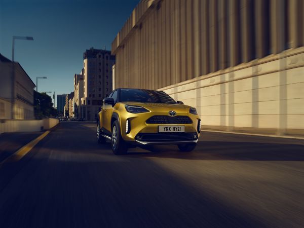 Gelber Toyota Yaris Cross fährt durch die sonnigen Straßen einer Innenstadt
