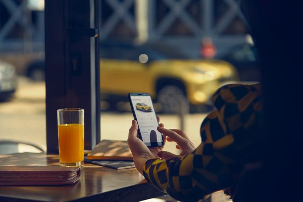 Woman at table on phone looking at Toyota Yaris Cross