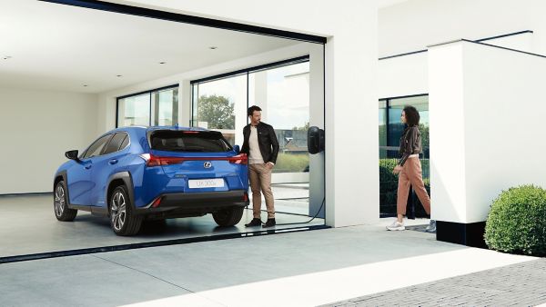 two people standing next to a Lexus UX 300e