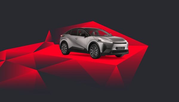 Ein silberner Toyota C-HR+ vor einem abstrakten Hintergrund mit roten Kacheln