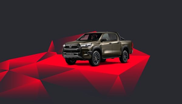 Ein olivgrüner Toyota Hilux vor einem abstrakten Hintergrund mit roten Kacheln