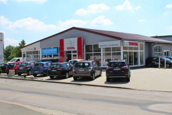Das Gebäude des Autohaus Farnbacher von außen mit mehreren Toyota Fahrzeugen davor