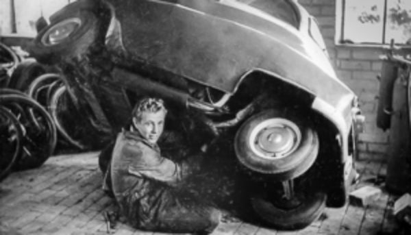 Ein Schwarzweiß-Bild von einem Mechaniker, der an einem Fahrzeug arbeitet