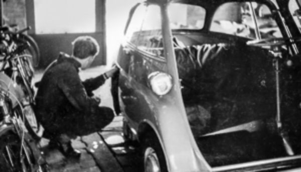 Ein Schwarzweiß-Bild von einem Mechaniker, der an einem Fahrzeug arbeitet