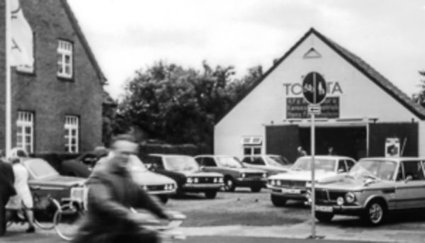 Ein Schwarzweiß-Bild von einem Innenhof mit mehreren alten Toyota-Fahrzeugen