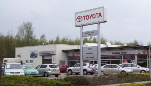 Toyota-Fahrzeuge stehen vor einem modernen Autohaus mit Glasfassade.