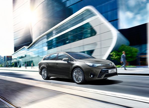 Toyota Avensis driving next to modern building