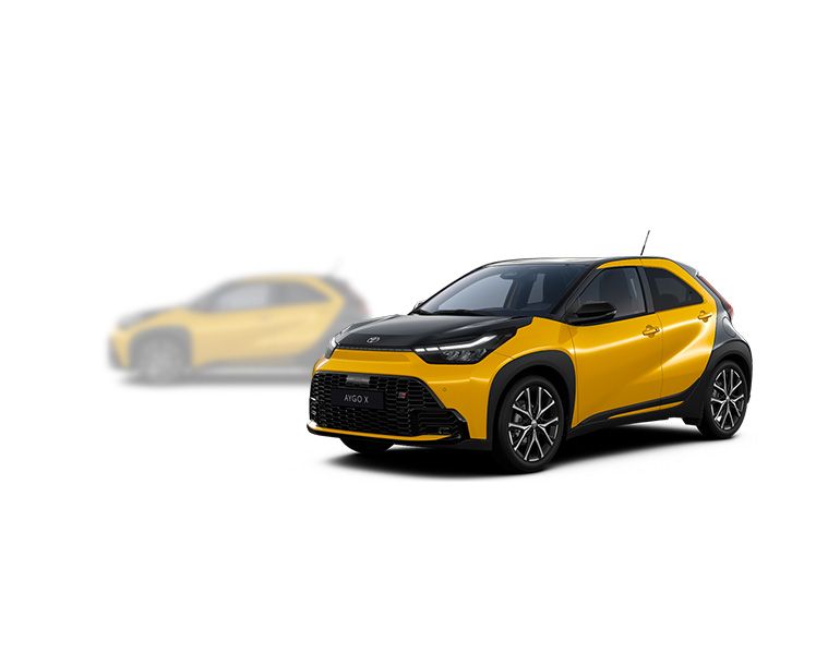 Gelber Toyota Aygo X steht diagonal zur Kamera, im Hintergrund ist unscharf ein heller Aygo X zu erkennen