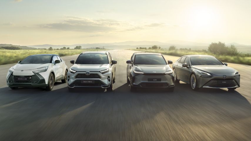 Toyota C-HR, RAV4 Hybrid, Toyota bZ4X i Mirai jadą obok siebie drogą poza miastem.
