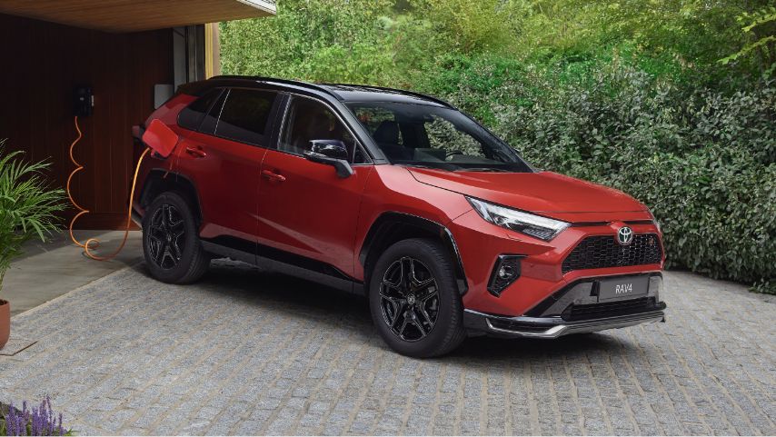 Toyota RAV4 Plug-in stoi przed posesją podczas ładowania ze stacji domowej.