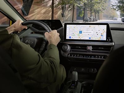 Conduite d’un véhicule Toyota avec écran central affichant la navigation GPS et technologies embarquées.