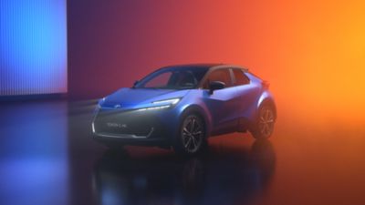 Ein Toyota C-HR steht vor einem Hintergrund mit orange-blauer Lichtinszenierung.