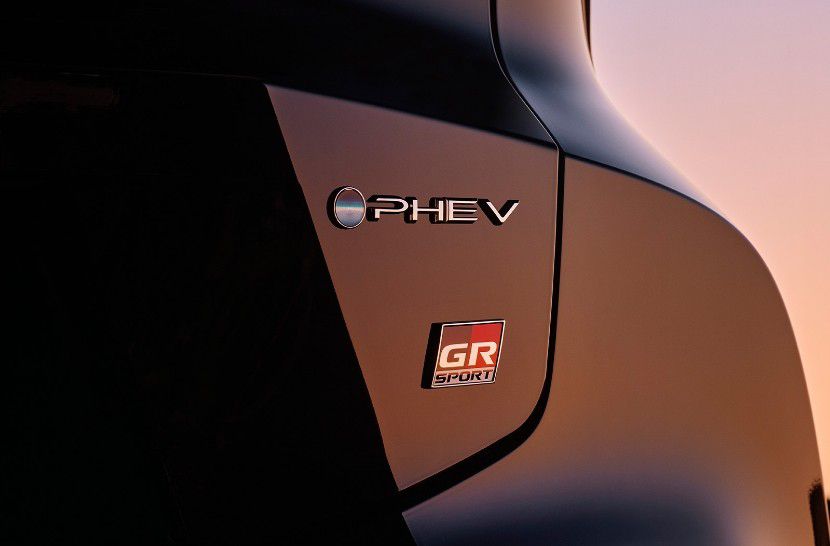 Zbliżenie dwóch logotypów na nadwoziu Toyoty: PHEV i GR SPORT.