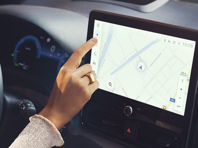 Palec wskazujący dłoni kobiecej przy ekranie nawigacji w samochodzie.